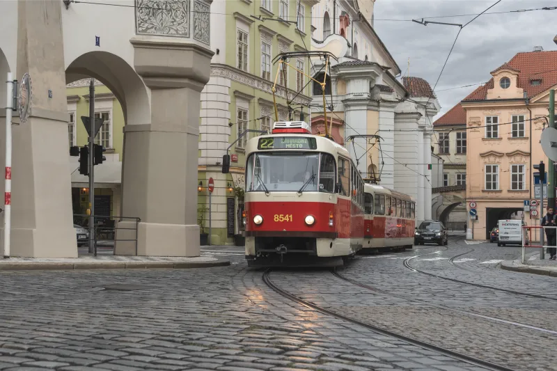 Klassische Straßenbahn fährt durch die Altstadt von Prag unter einem historischen Bogen
